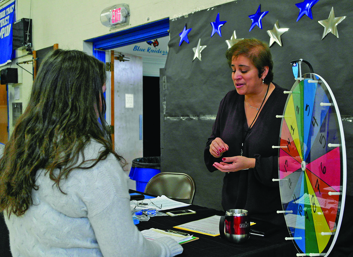 PTO member Rima Crepeau helps a student spin the  Wheel of Fortune