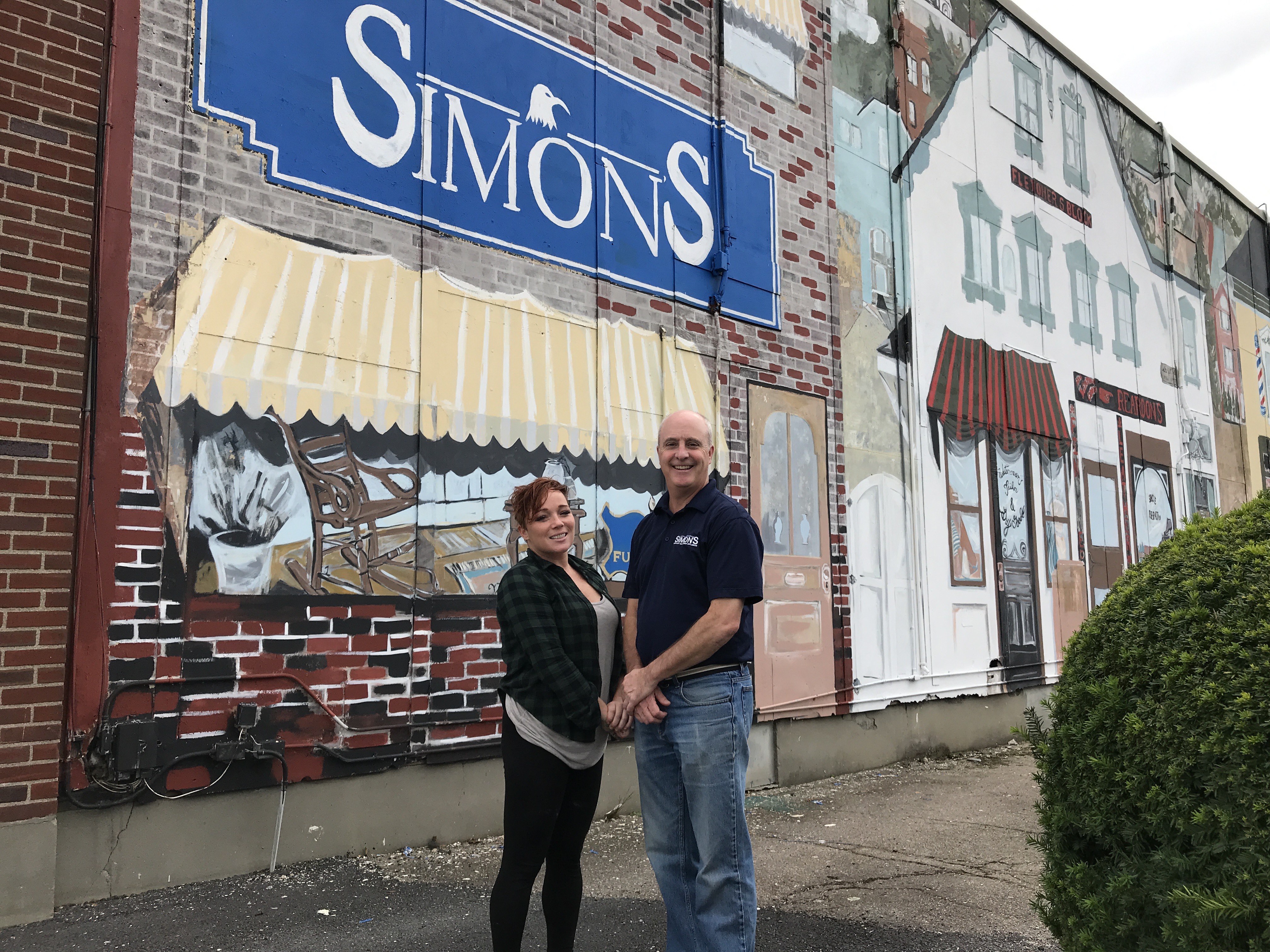 Artist Katelyn Chandler and Simon’s Furniture owner Kirk Simon are shown here with the newly revamped downtown mural.