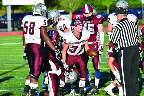 Kurt Hopkins hands the ball to an official after scoring one of his three touchdowns against Dedham.